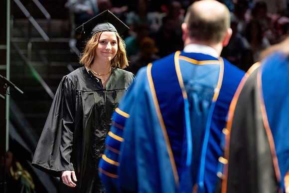 Graduates walk across the stage.