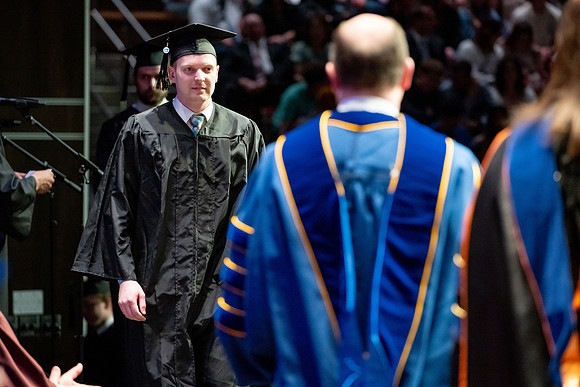 Graduates walk across the stage.