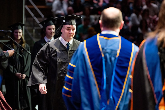 Graduates walk across the stage.
