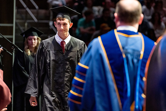 Graduates walk across the stage.
