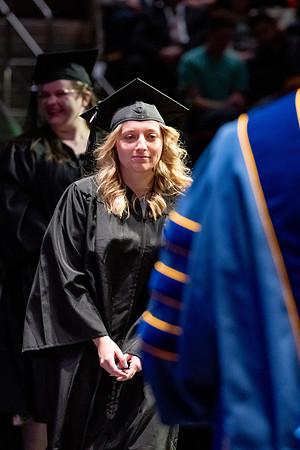 Graduates walk across the stage.