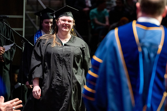 Graduates walk across the stage.