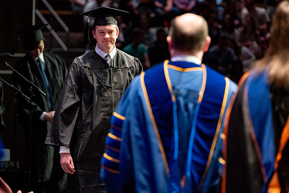 Graduates walk across the stage.