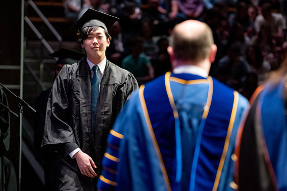 Graduates walk across the stage.
