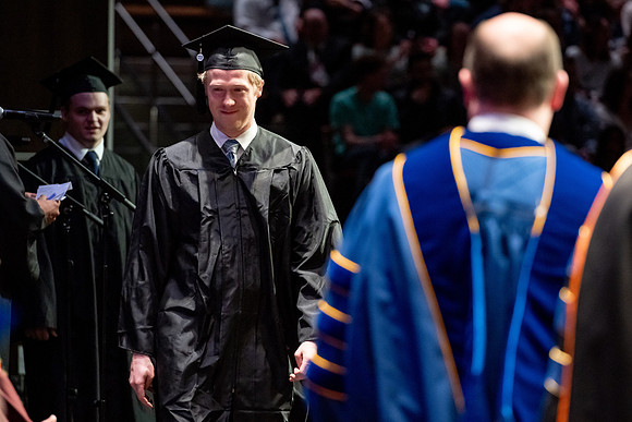 Graduates walk across the stage.