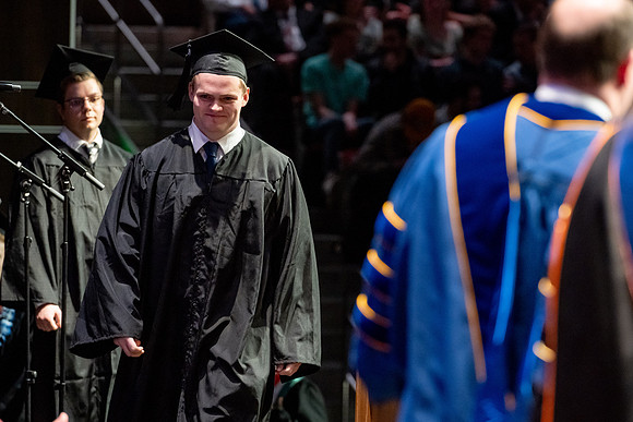 Graduates walk across the stage.