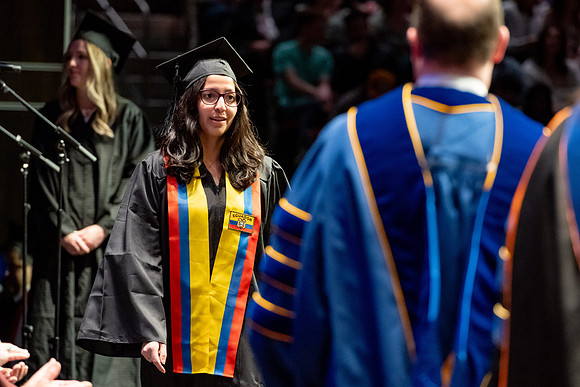 Graduates walk across the stage.