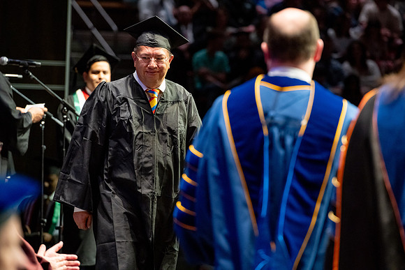 Graduates walk across the stage.