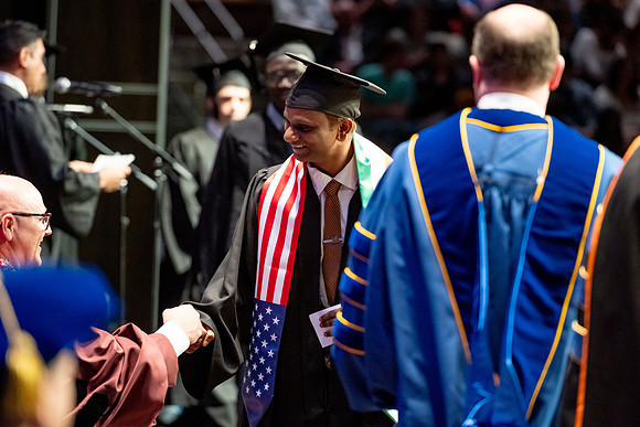 Graduates walk across the stage.
