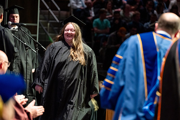 Graduates walk across the stage.
