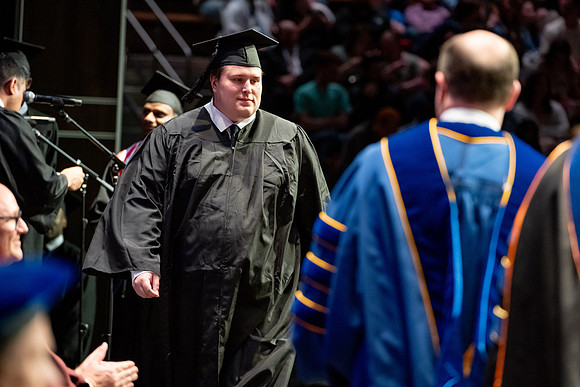 Graduates walk across the stage.