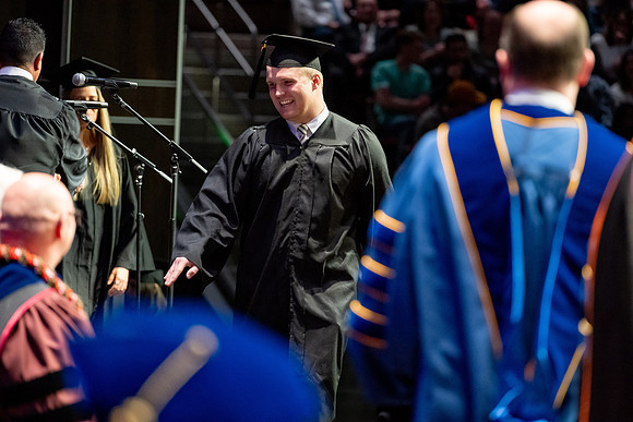 Graduates walk across the stage.