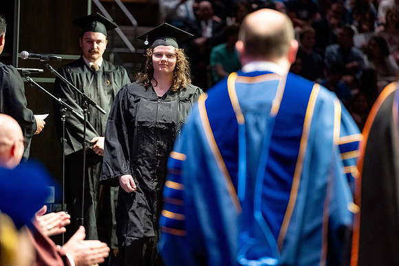 Graduates walk across the stage.