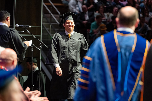 Graduates walk across the stage.