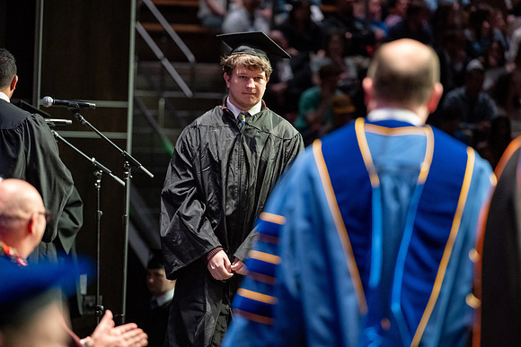 Graduates walk across the stage.