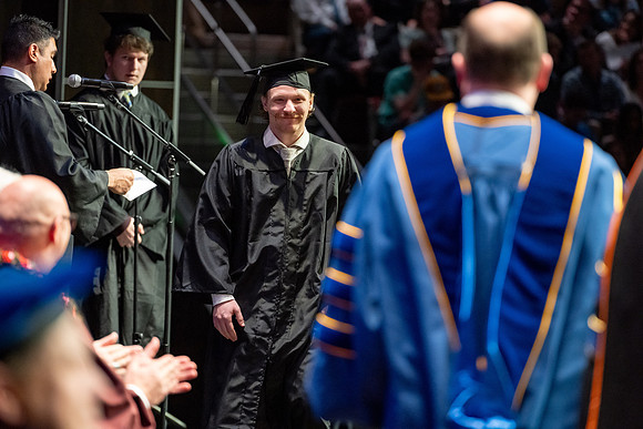 Graduates walk across the stage.