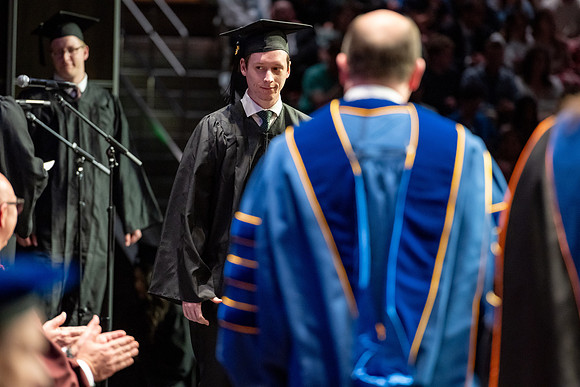 Graduates walk across the stage.