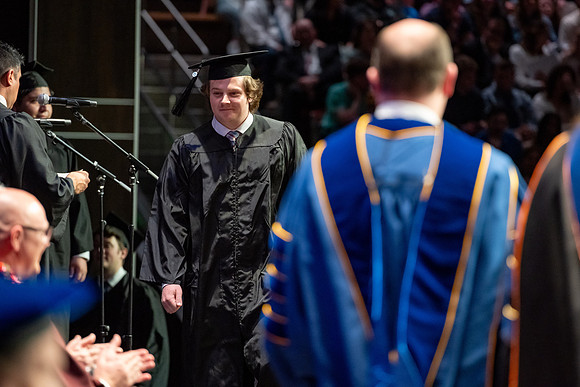 Graduates walk across the stage.
