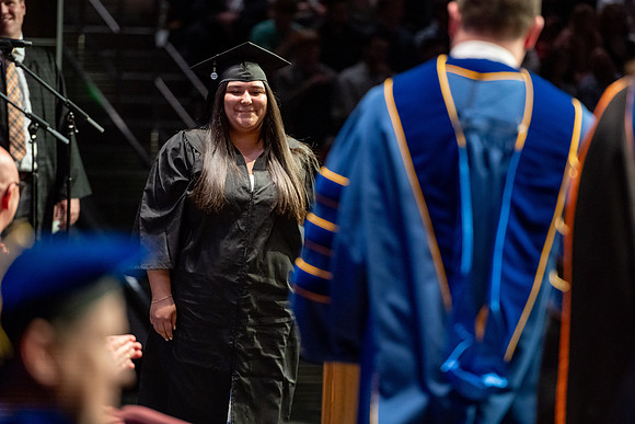 Graduates walk across the stage.