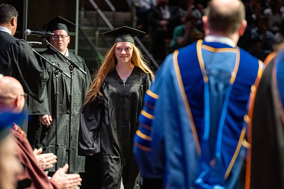 Graduates walk across the stage.
