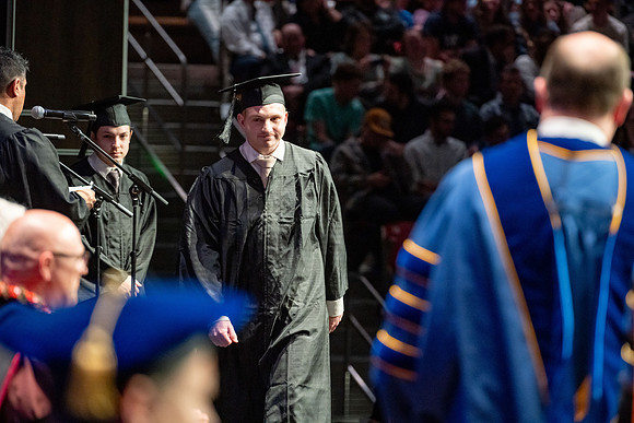 Graduates walk across the stage.