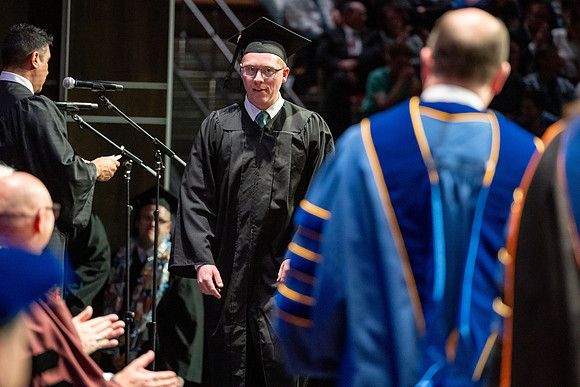 Graduates walk across the stage.