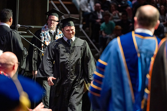 Graduates walk across the stage.