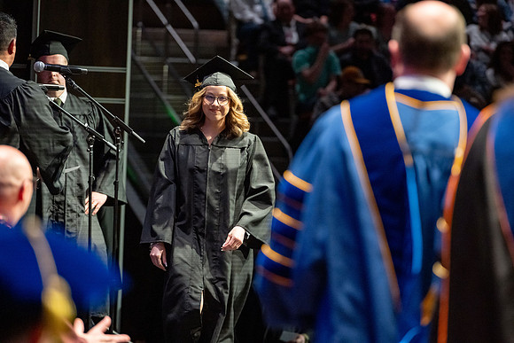 Graduates walk across the stage.