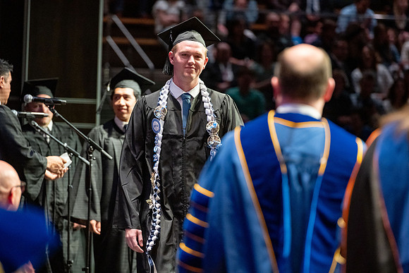 Graduates walk across the stage.