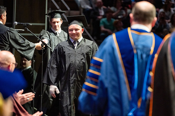 Graduates walk across the stage.