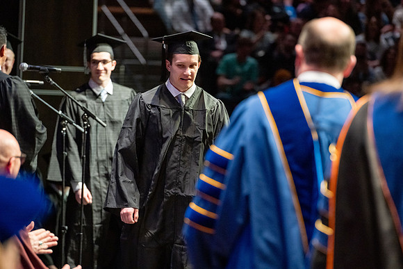 Graduates walk across the stage.