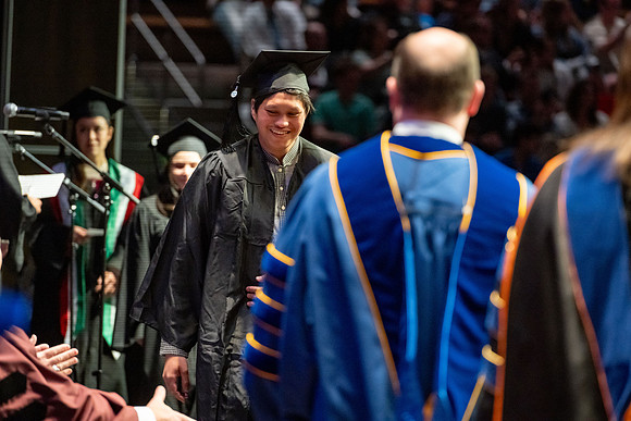 Graduates walk across the stage.