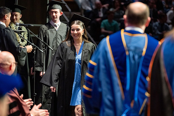 Graduates walk across the stage.