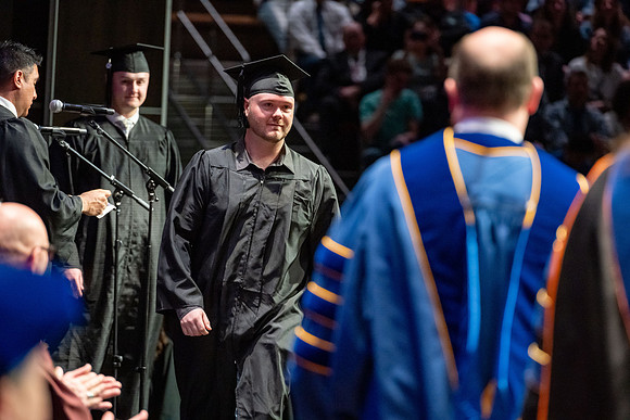 Graduates walk across the stage.