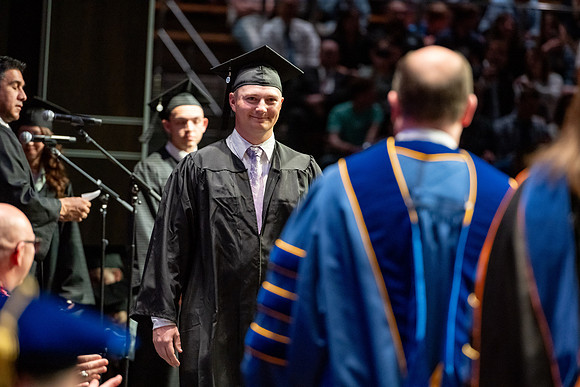 Graduates walk across the stage.