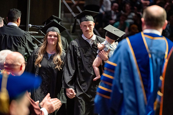 Graduates walk across the stage.