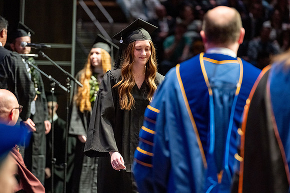 Graduates walk across the stage.