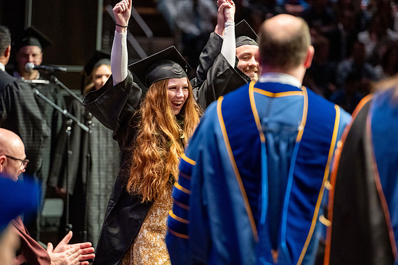 Graduates walk across the stage.