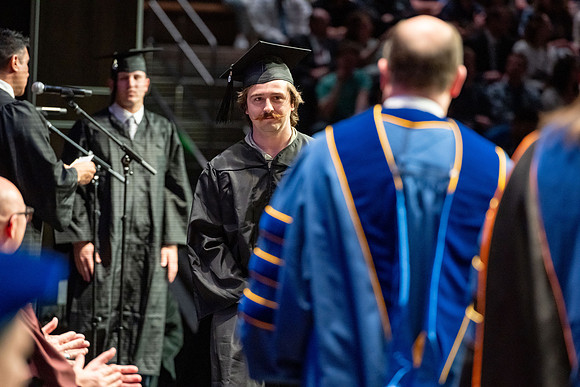 Graduates walk across the stage.