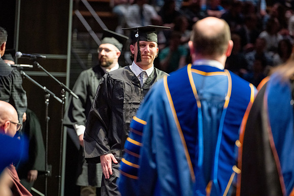 Graduates walk across the stage.