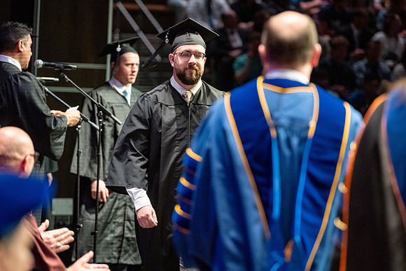 Graduates walk across the stage.