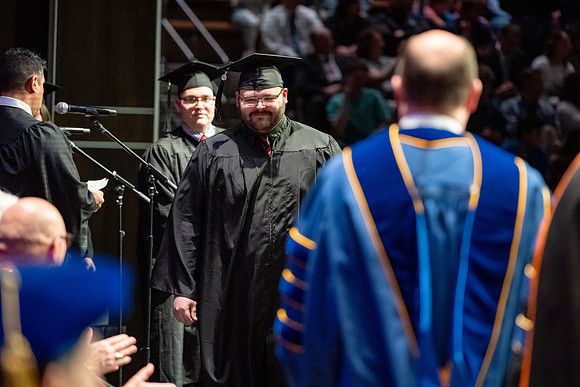 Graduates walk across the stage.