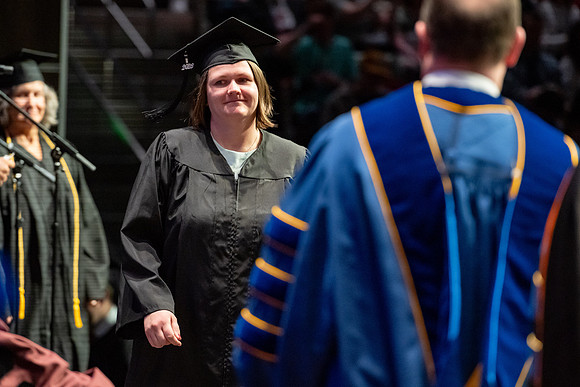 Graduates walk across the stage.
