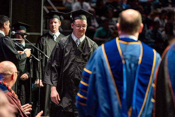 Graduates walk across the stage.