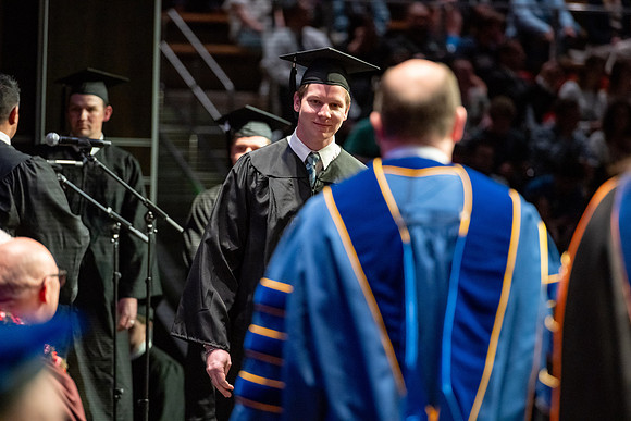 Graduates walk across the stage.