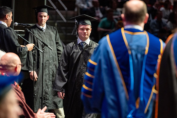 Graduates walk across the stage.