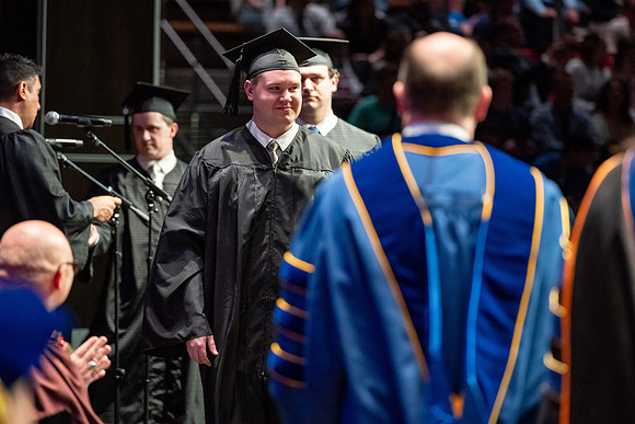 Graduates walk across the stage.