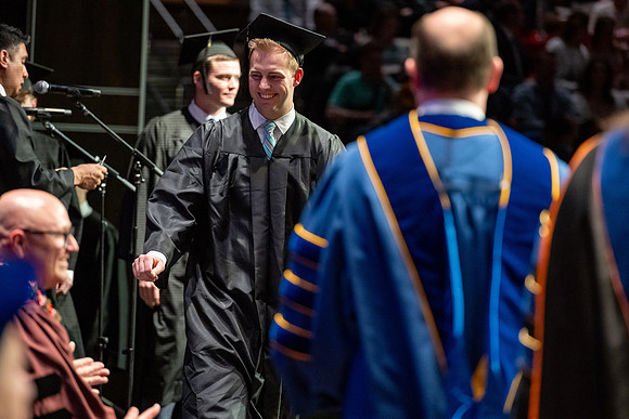 Graduates walk across the stage.
