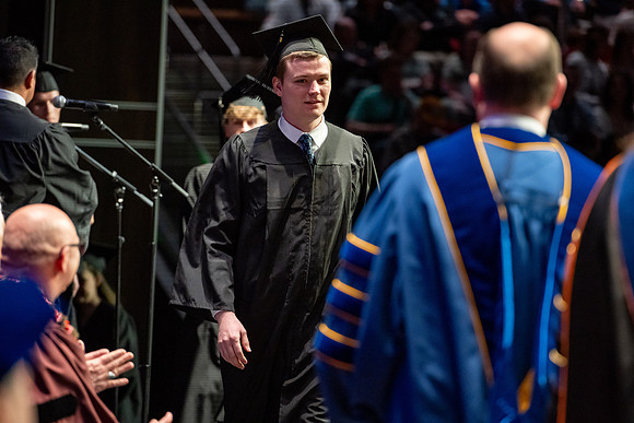 Graduates walk across the stage.