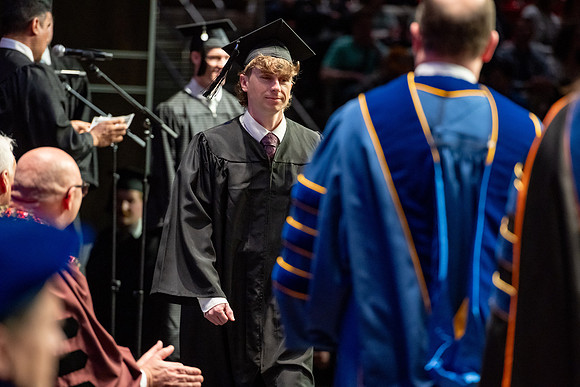 Graduates walk across the stage.